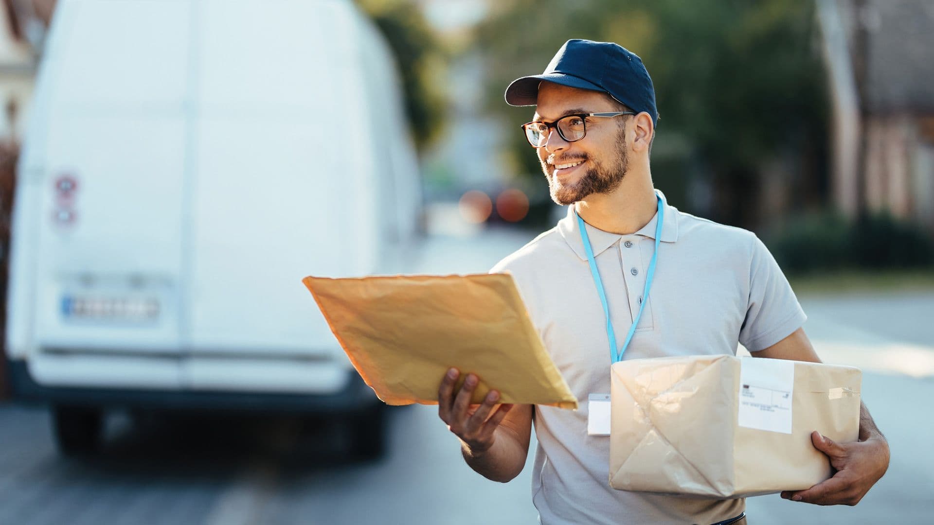 a delivery man is holding a package and a piece of paper in front of a van .